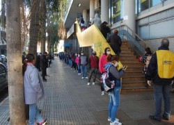 Beneficiarios de planes sociales haciendo cola con barbijos